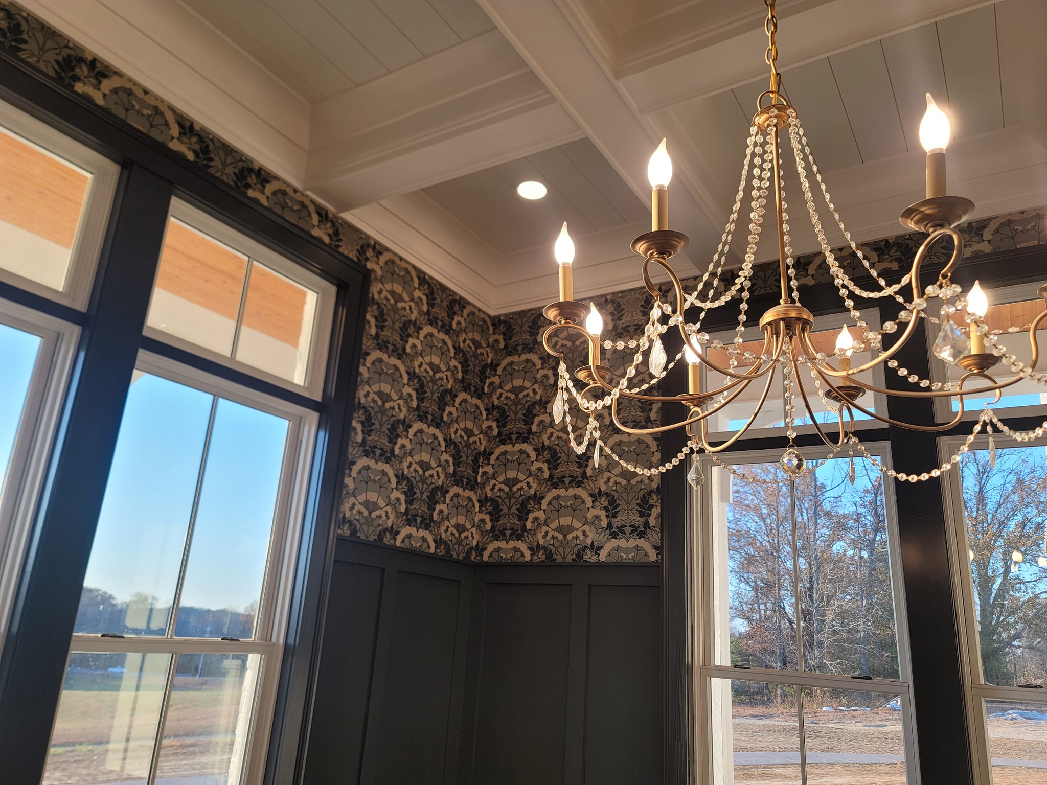 Dark damask wallpaper with crystal chandelier by Lillian's Interiors