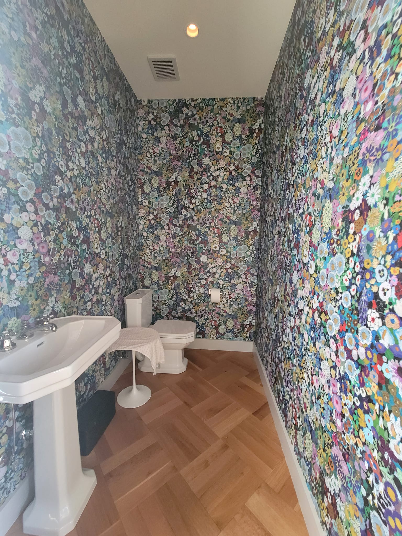 Colorful floral wallpaper powder room with herringbone floor by Lillian's Interiors